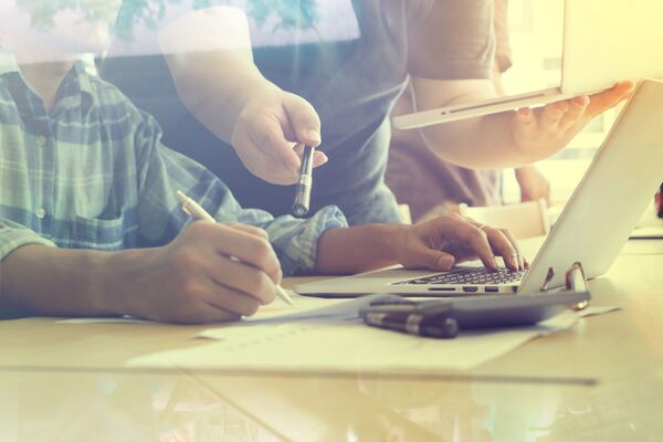 People working at laptops around a desk in a bright office